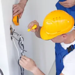 Elektryk w żółtym kasku pracuje przy instalacji, zastanawiając się, ile zarabia elektryk w Norwegii.