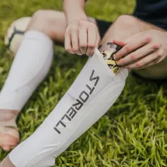 Fußballer legt ein Schienbein Splint mit Tarnmuster in eine weiße Hülle.