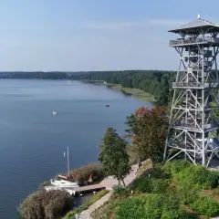 Wieża widokowa we Wdzydzach góruje nad jeziorem, oferując malowniczy widok na wodę i las.