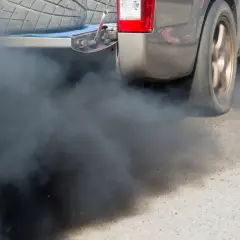 Z rury wydechowej wydobywa się gęsty, czarny dym, który zasłania tył samochodu.