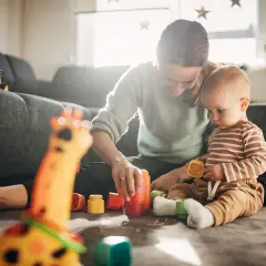 Mama i 7-miesięczne dziecko bawią się kolorowymi klockami na dywanie. Radość i nauka przez zabawę.