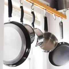 Une astuce rangement casserolier : des poêles suspendues à une barre en bois, libérant de l'espace dans les placards.