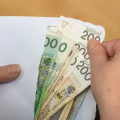 Dłonie wyciągają z koperty polskie banknoty. To może być pomoc z ZUS, np. renta rodzinna po mężu.