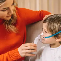 Mamma assiste il bambino con inalatore per il broncospasmo.