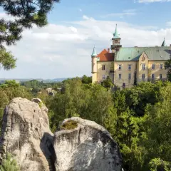 Zamek na skale, otoczony zielenią, to jedna z malowniczych atrakcji w Czechach. Widok na skalne formacje i krajobraz.