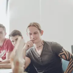Junge Männer im Gespräch, einer mit Tattoos, vielleicht beim bachelor physiotherapie berufsbegleitend.