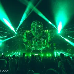 Niesamowita scena z zielonymi światłami i głową z cyframi na Sunrise Festival. Tłum bawi się przy muzyce, czekając na ogłoszenie line-up.