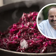 Ein Koch lächelt, während er dampfendes Blaukraut verfeinert.