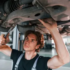 Mechanik naprawia zawieszenie auta, podejrzewając jazdę z uszkodzoną tuleją wahacza.