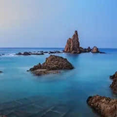 Rocas emergiendo de aguas turquesas en el fondo marino de Cabo de Gata. El cielo se funde con el mar en un amanecer sereno.