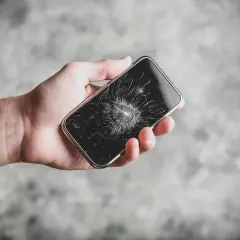 Dłoń trzyma pęknięty telefon. Zastanawiasz się, ile trwa wymiana szybki w telefonie?