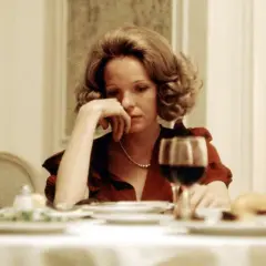 En melankolisk Diane Keaton vid ett middagsbord, en scen som påminner om hennes ikoniska roller i filmer med Diane Keaton.