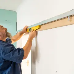 Un homme utilise un niveau à bulle pour assurer la pose parfaite d'une porte coulissante.