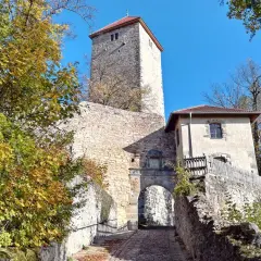 Herbstliche Bäume umgeben die **Ruine Lichtenburg** mit ihrem markanten Turm und Torbogen.