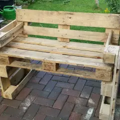 Ein selbstgebautes Palettensofa steht auf einer Terrasse. Die Sitzfläche und Rückenlehne sind aus Holzpaletten gefertigt.