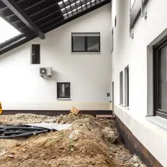 Baustelle am Altbau: Ein Bagger und Rohre liegen im Erdreich. Der Kellerbereich ist freigelegt, was bei solchen Arbeiten normal ist.