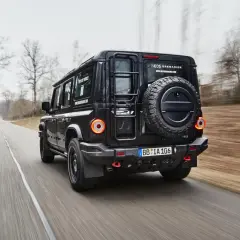 Czarny INEOS Grenadier, jeden z nowych, potężnych **marek samochodów terenowych**, pędzi leśną drogą.
