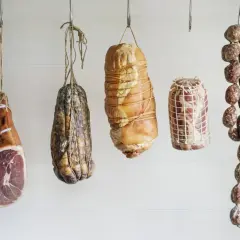 Wędzenie bez parzenia: wiszące szynki, salami i inne mięsne specjały, gotowe do dojrzewania.