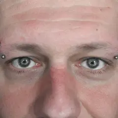 Zbliżenie na twarz z kolczykami w brwiach. Zastanawiasz się, ile kosztuje nostril?