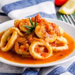 Anelli di calamari in umido con pomodoro e rosmarino, un piatto saporito e invitante.