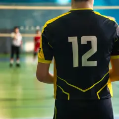 Męski strój siatkarski z numerem 12 na plecach. Zawodnik gotowy do gry na boisku.