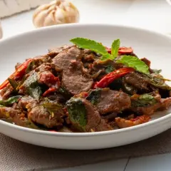 Aksamitne kawałki wołowiny z bazylią i papryczką chili, aromatyczne wołowina po tajsku, podane w białej misce.