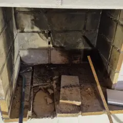 Insats skorsten i ett öppet utrymme med tegelväggar. Verktyg och mätband ligger redo för arbete.