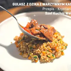 Gulasz z dzika z kaszotto warzywnym. Łyżka nakłada aromatyczne mięso na talerz pełen zdrowego kaszotto.
