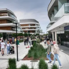 Spacer po nowoczesnej promenadzie w Świnoujściu, gdzie liczne atrakcje czekają na turystów. Ludzie spacerują, sklepy i apartamenty zachwycają architekturą.