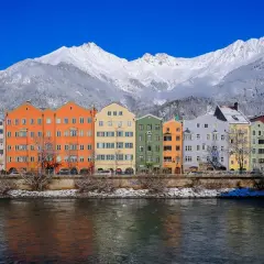 Kolorowe kamienice nad rzeką, w tle ośnieżone góry. To piękne Innsbruck atrakcje, które warto zobaczyć zimą.