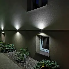 Nowoczesny kinkiet na balkon oświetla ścieżkę i rośliny, tworząc nastrojową atmosferę wieczorem.