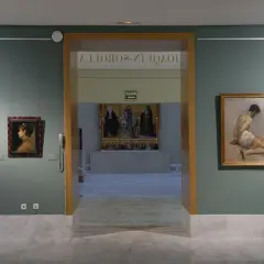 Wnętrze muzeum sztuk pięknych w Walencji. Obrazy wiszą na zielonych ścianach, a marmurowa podłoga odbija światło.