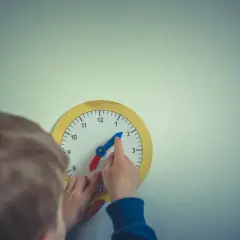 Dziecko uczy się odczytywać godzinę na zabawkarskim zegarze. Prosta nauka zegara to świetna zabawa!