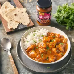 Pyszny kurczak tikka masala z ryżem, podany z plackami i świeżą kolendrą. Idealny na szybki obiad.