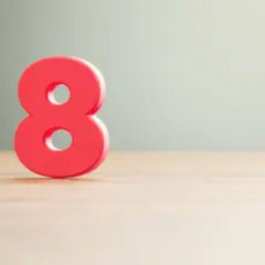 Número 8 rojo sobre superficie de madera, simbolizando el significado número 8 en lo espiritual: abundancia, equilibrio y poder infinito.