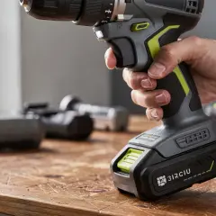 Main d'un bricoleur tenant une visseuse sans fil. La question "peut on mettre une batterie plus puissante sur une visseuse" est au cœur de cette image.