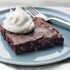 En saftig brownie med nötter, toppad med vispad grädde, redo att avnjutas. Perfekt för ett enkelt brownie recept.
