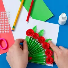 Tworzenie kartki z okazji Dnia Mamy: zielony wachlarz z czerwonymi różami i perłami, nożyczki, klej, kredki.