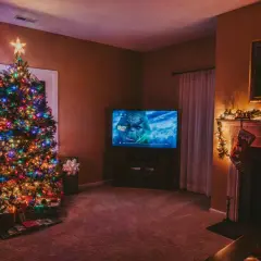 Albero di Natale illuminato, regali sotto, e il Grinch in TV. Perfetto per ascoltare canzoni di Natale in inglese testo.
