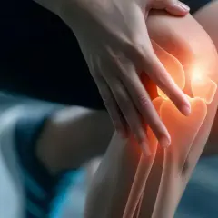 Eine Hand berührt ein Knie, das rot leuchtet, was auf knie schmerzen hindeutet.
