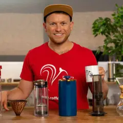 Mann mit verschiedenen Kaffeebereitern, die zeigen, welche Kaffeezubereitung die beste ist.