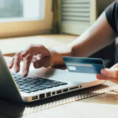 Osoba wpisuje dane karty kredytowej mBank na laptopie, realizując płatność online.