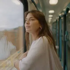 En ung kvinna tittar ut genom tågfönstret, drömmande om sin interrail resa.