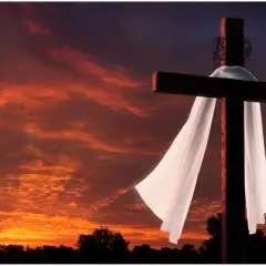 Kreuz mit Dornenkrone und Leichentuch vor dramatischem Sonnenuntergang. Ein Symbol für Karfreitag, den Feiertag der Besinnung.