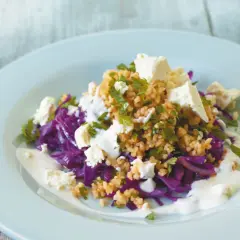 Rotkohl Rezepte mal anders: Ein bunter Salat mit Rotkohl, Bulgur, Feta und Joghurt-Dressing auf einem hellblauen Teller.