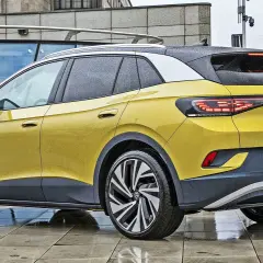 Żółty VW ID.4 z czarnym dachem i felgami stoi na mokrym chodniku.