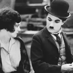 Charlie Chaplin och en kvinna i en klassisk chaplin film. Han ser bekymrad ut medan hon betraktar honom.