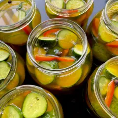 Słoiki pełne chrupiących ogórków z papryką i przyprawami, gotowe na zimę. Te ogórki w curry zachwycą smakiem!