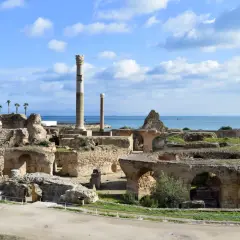 Antike Ruinen von Karthago heute, mit Säulen und Bögen, die sich gegen das blaue Meer und den Himmel abheben.