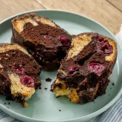 Saftiger Marmorkuchen mit Kirschen, überzogen mit Schokolade, auf einem Teller angerichtet.